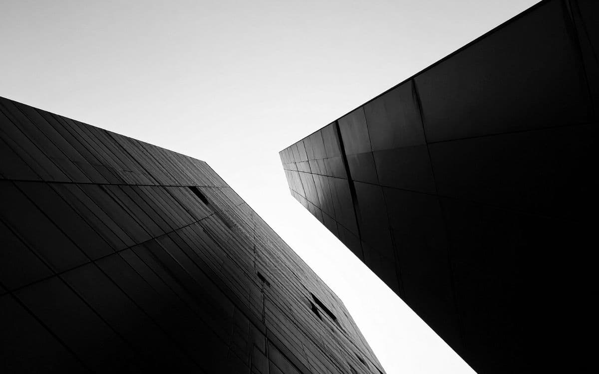 Dark angled facades against a white sky